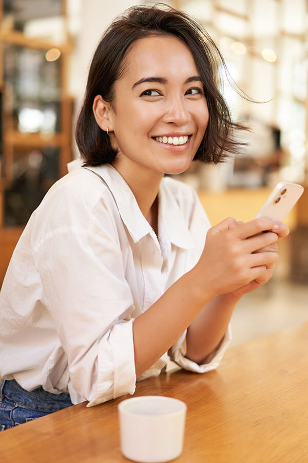 Uma mulher sorridente acaba de fazer um pedido pelo celular com um menu de QRcode